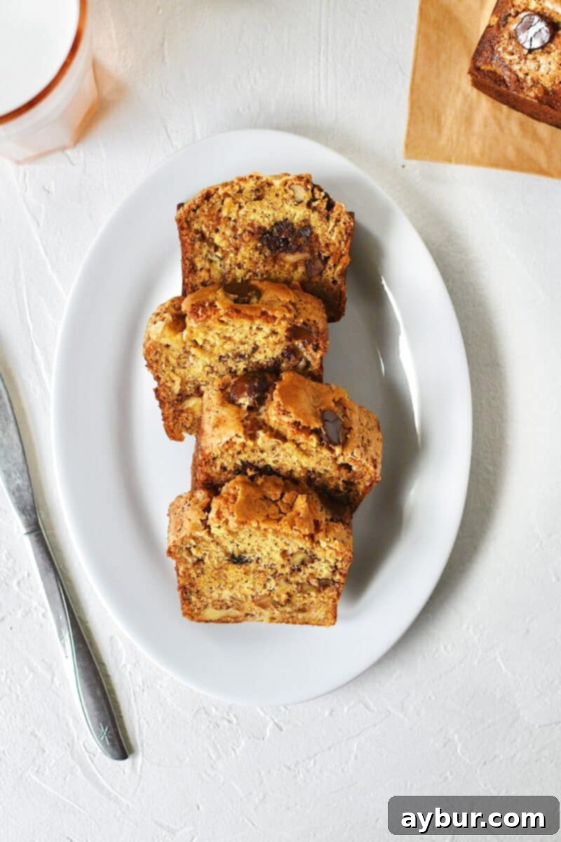 Nutty Brown Butter Banana Loaf 9 Close-up of freshly baked slices of browned-butter banana bread on a plate, showcasing the moist interior, walnuts, and melted chocolate chips, ready to be enjoyed.