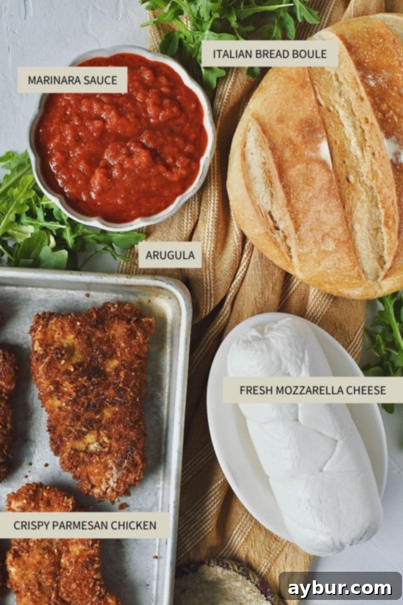 A vibrant selection of fresh ingredients laid out, including crispy parmesan chicken, marinara sauce, fresh mozzarella cheese, arugula, and Italian bread slices, ready to make a delicious Parmesan Chicken Sandwich.