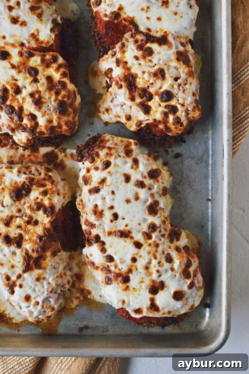 Crispy Parmesan Chicken, smothered in marinara and mozzarella, perfectly melted and browned after baking, bubbling enticingly.
