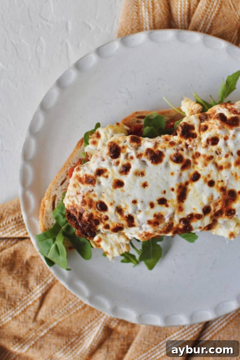 The Parmesan Chicken Sandwich coming together: toasted bread, marinara, arugula, and the star crispy parmesan chicken with melted mozzarella.