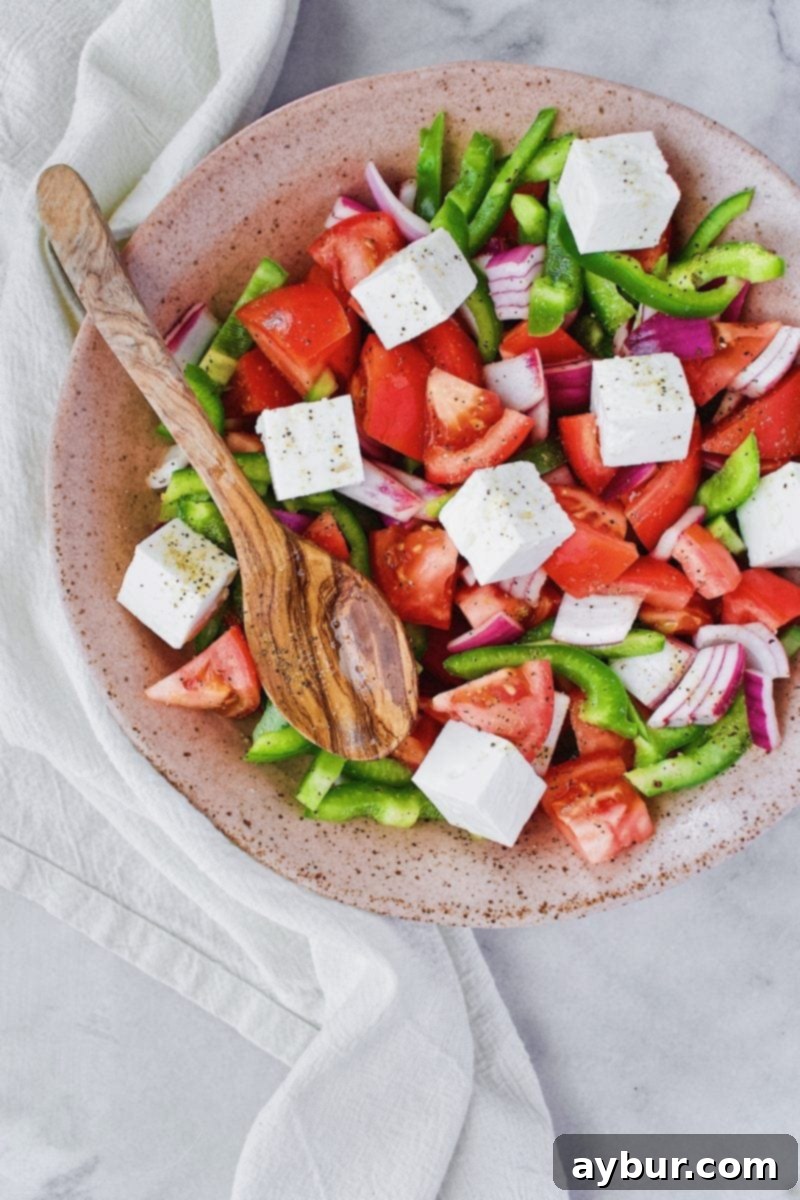 Freshly tossed Greek Salad in a large bowl, ready to be served, showing the mix of vegetables and the delicious dressing.