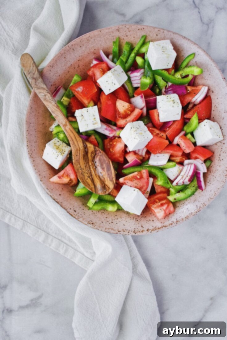 Traditional Greek Salad topped with a generous slab of Feta Cheese Cubes, ready to be served.