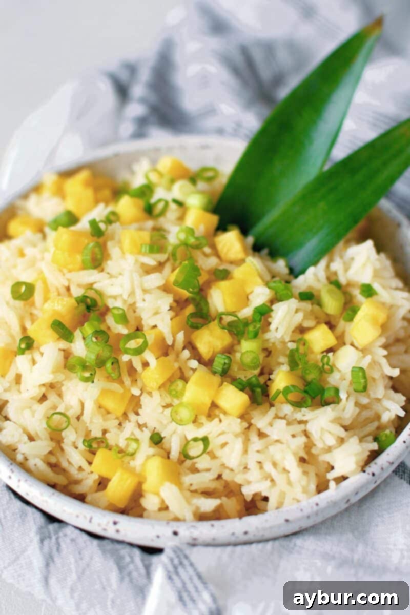 Tropical Coconut Pineapple Rice 2 A beautifully presented bowl of Pineapple Coconut Rice, garnished generously with fresh diced pineapple and finely chopped green onions, ready to serve.