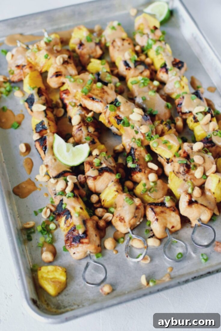 Tropical Peanut Chicken Skewers 9 Pineapple Peanut Chicken Skewers fresh off the grill topped with peanut sauce, chopped green onions, and chopped peanuts.
