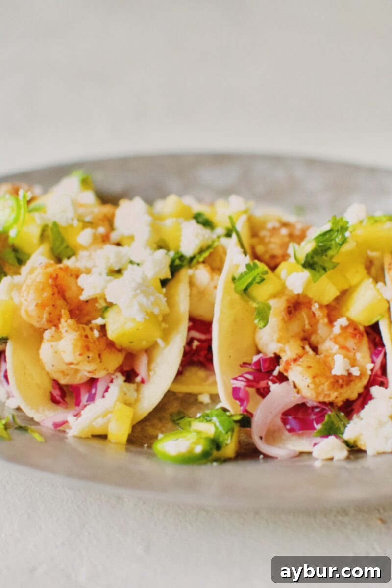 A vibrant platter of freshly prepared Baja Shrimp Tacos, garnished with fresh cilantro and lime wedges.