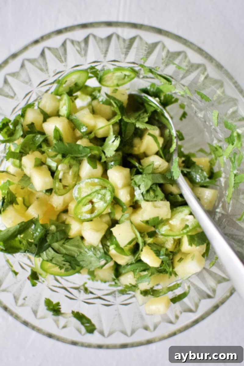 A small bowl filled with vibrant, freshly prepared pineapple pico, showcasing its bright colors and textures.