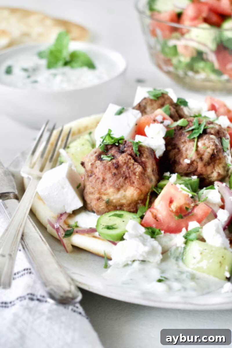 A beautifully presented plate of Greek Meatballs with fresh Greek Salad and creamy Tzatziki, embodying a delightful Mediterranean meal.