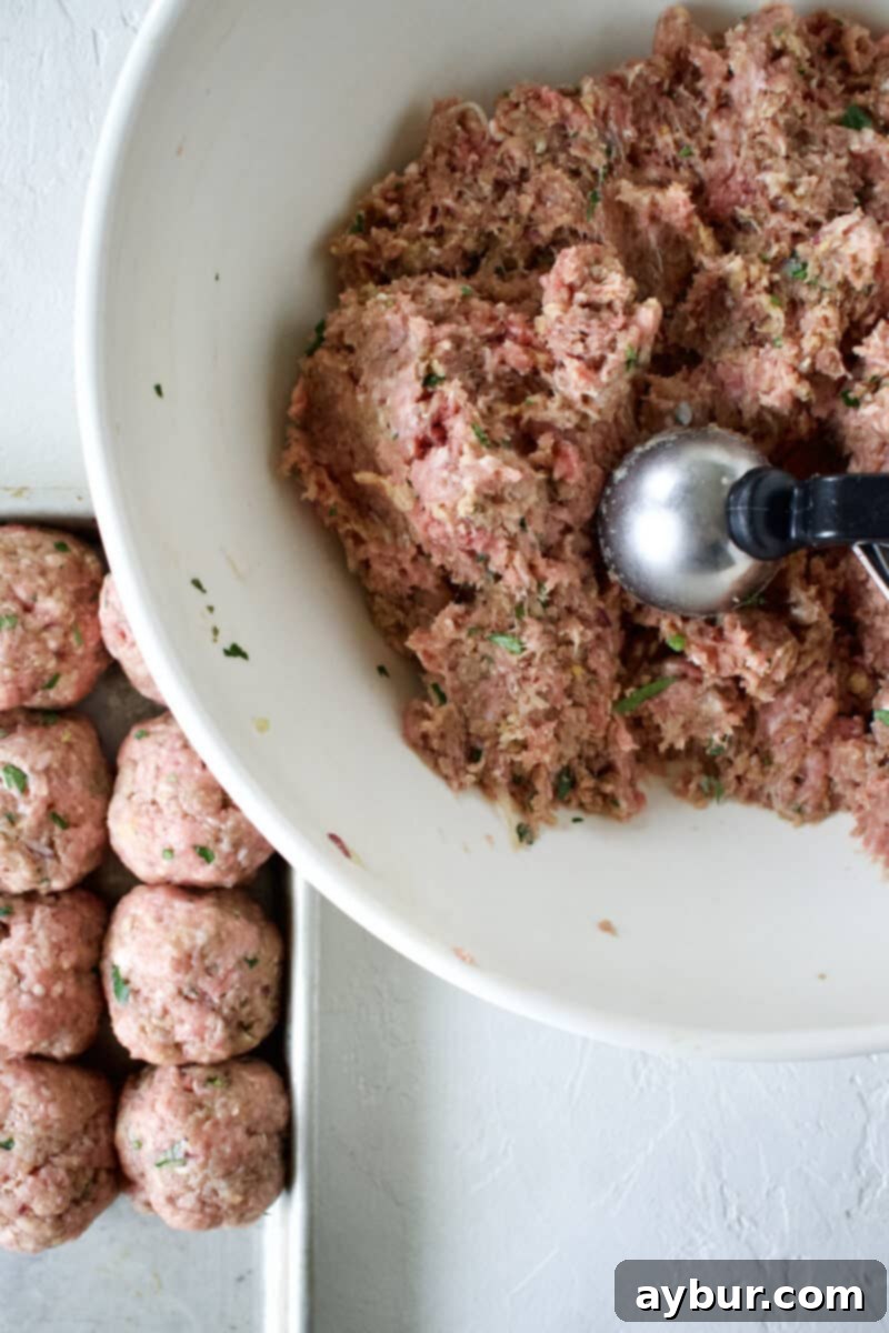 The process of hand-forming individual Greek Meatballs, ensuring uniform size and shape.