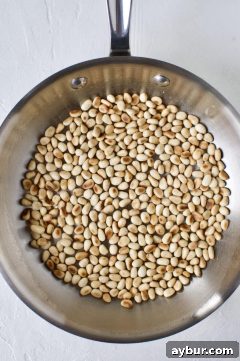 Pine nuts in a pan after toasting, showing a golden brown color.