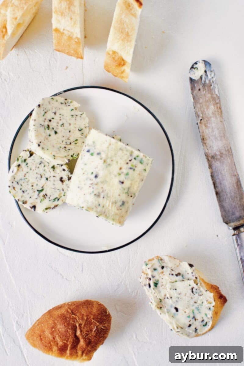 Gourmet Black Truffle Butter 4 Another view of the finished Black Truffle Butter log, expertly sliced and arranged on a elegant serving plate beside a knife, showcasing its rich texture and flecks of truffle and herbs.