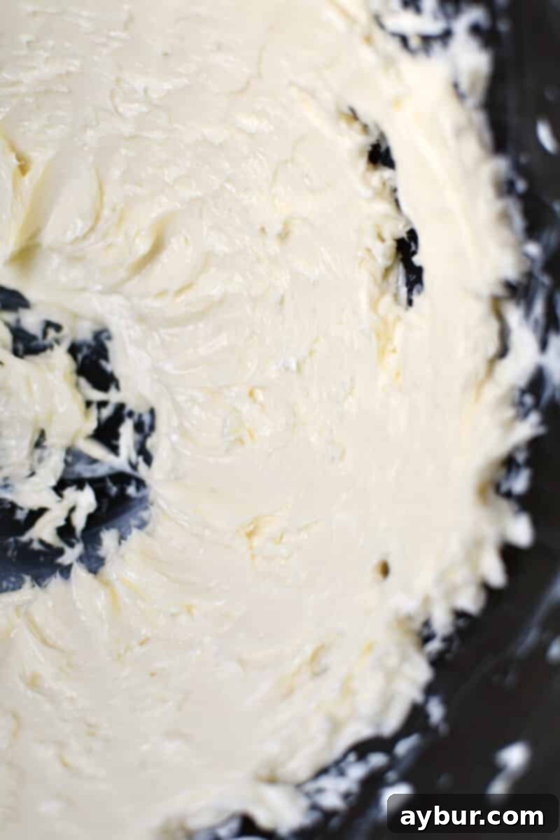 Gourmet Black Truffle Butter 5 Softened, premium butter being vigorously whipped to a pale, fluffy consistency in the pristine bowl of a stand mixer, indicating the first stage of compound butter preparation.