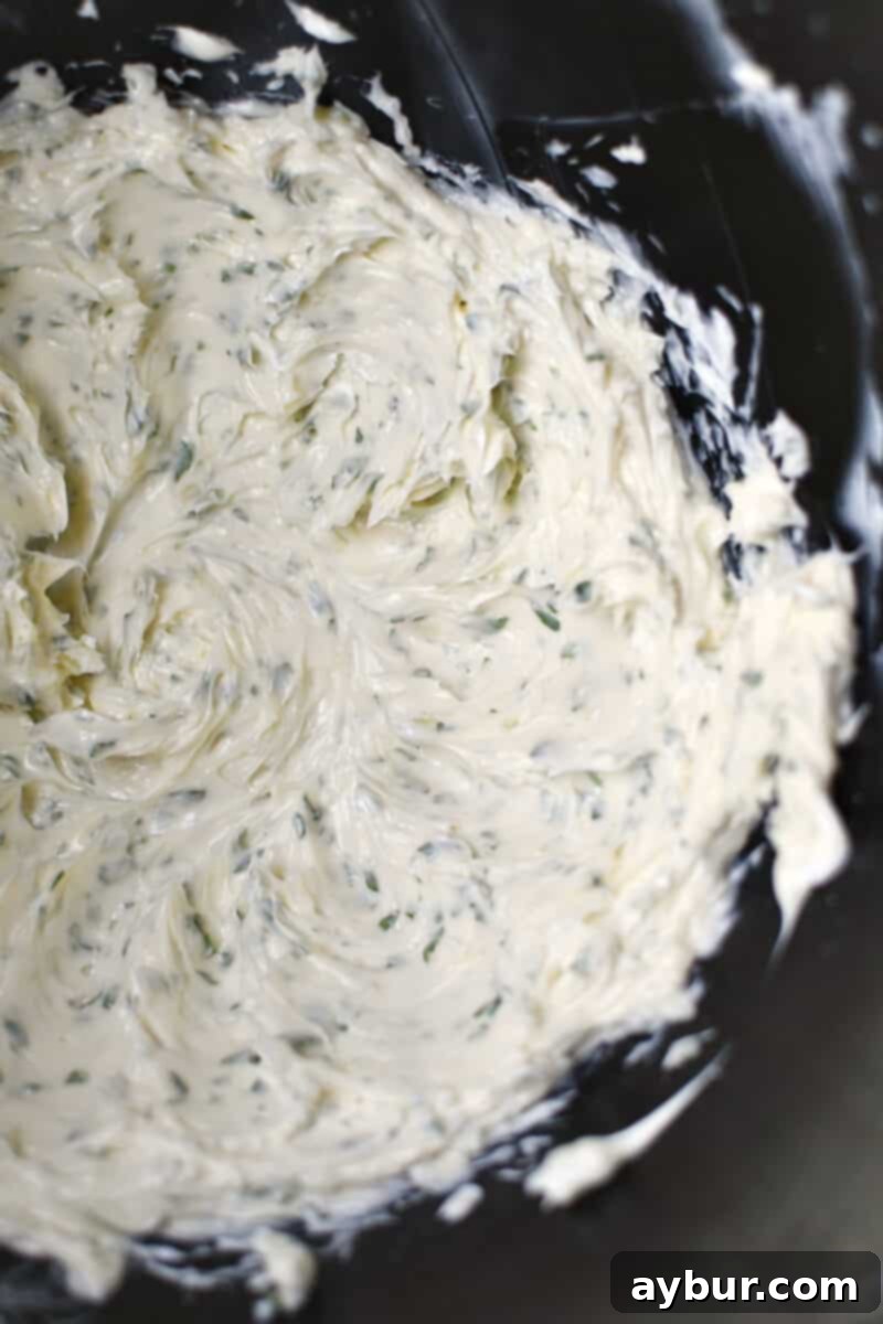 Gourmet Black Truffle Butter 6 Whipped butter in a stand mixer bowl, now enriched with freshly minced garlic and vibrant green parsley, ready for final mixing to incorporate these aromatic additions.
