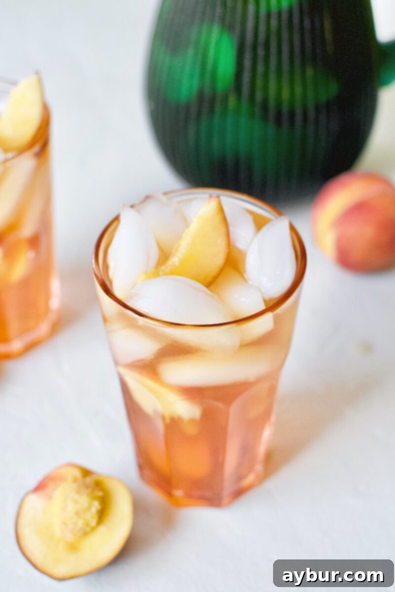 A refreshing glass of Peach Sangria, garnished with fresh peach wedges and ice, symbolizing a perfect summer beverage choice.