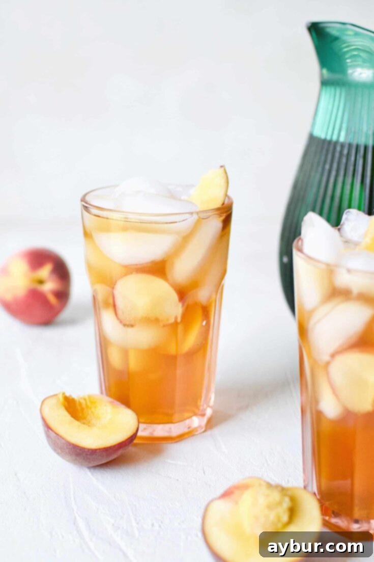 A refreshing glass of Peach Sangria in an ice-filled glass with peach wedges.