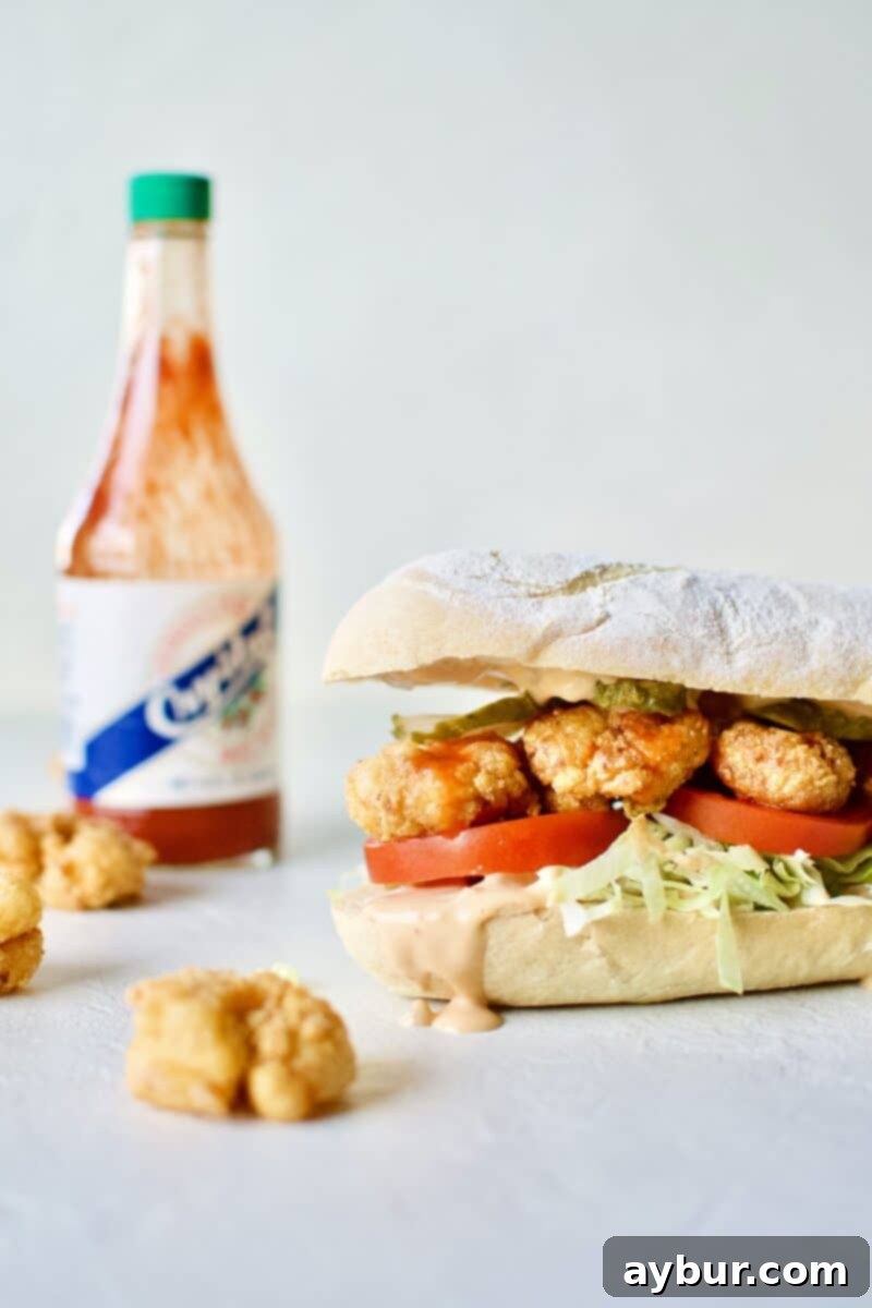 Fully assembled crispy Shrimp Po'boy Sandwich with fresh toppings and creamy remoulade sauce.