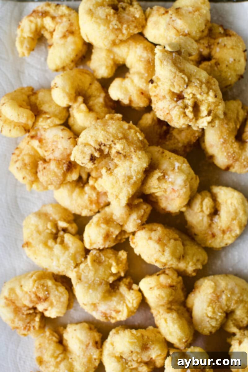 Freshly fried shrimp, golden brown and perfectly crispy, just removed from the deep fryer and ready to drain.