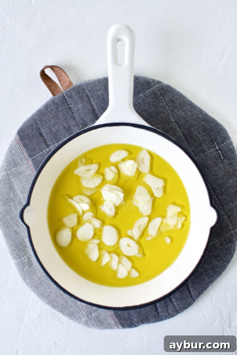 Smoky Baba Ghanoush with Golden Garlic 5 Thinly sliced garlic resting in a mini skillet, coated in olive oil.