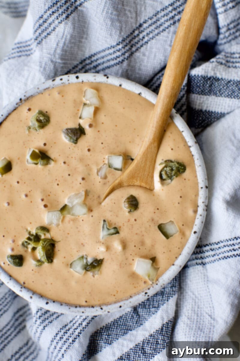 Effortless Remoulade Sauce 2 Easy homemade Remoulade Sauce prepared and served in a bowl, garnished with finely diced dill pickle and caper pieces, ready for dipping.