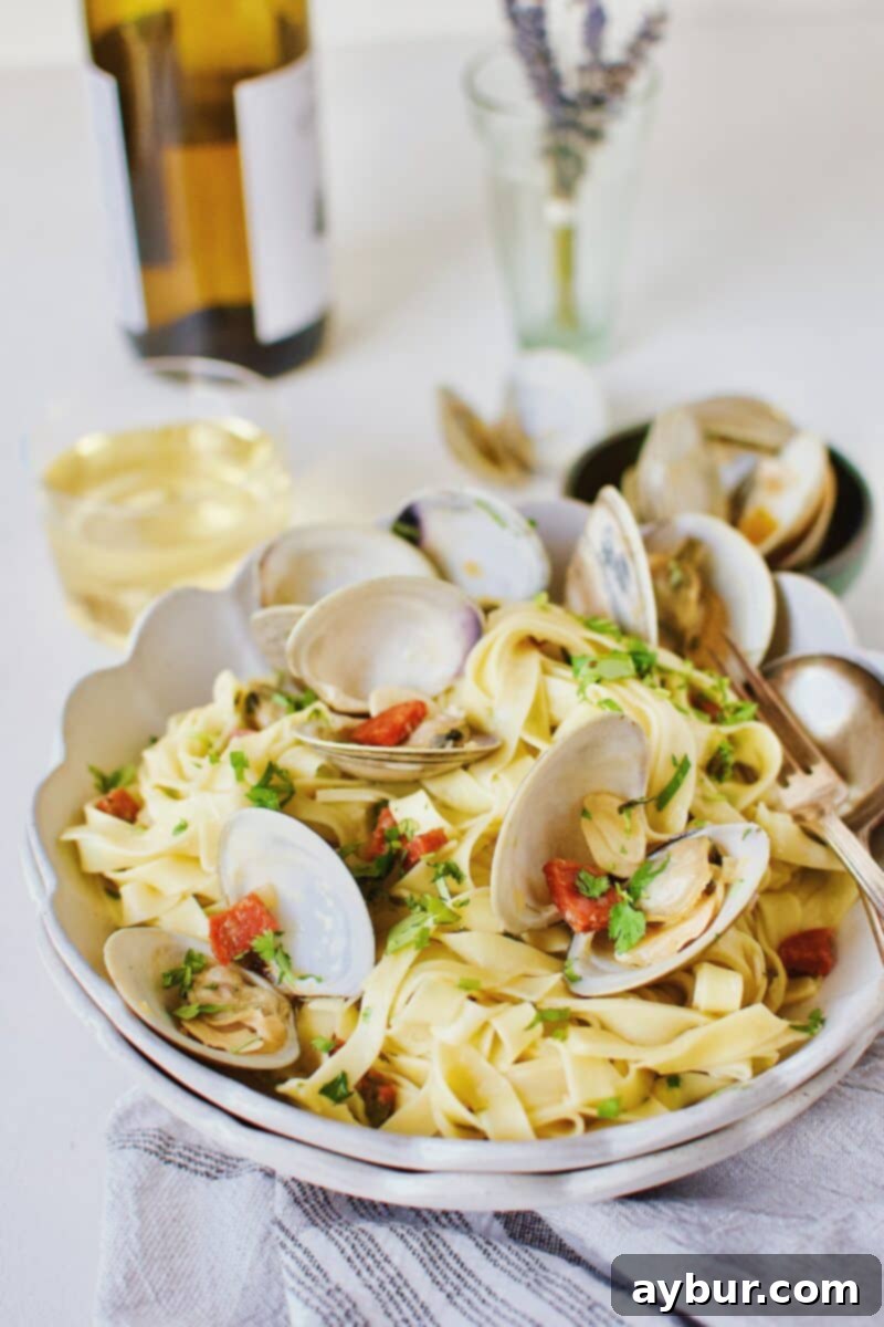 Linguine with Clams 2 A beautifully plated bowl of Linguine with Clam Sauce, garnished with fresh herbs, with a glass of crisp white wine in the soft-focus background, inviting viewers to indulge in a delightful seafood pasta experience.