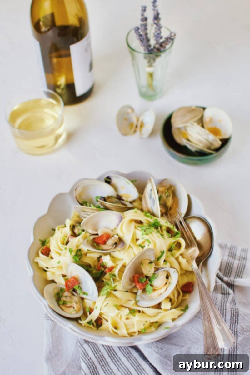 Linguine with Clams 15 A close-up of a serving of Linguine with Clam Sauce, featuring vibrant green herbs and perfectly cooked clams, with a wine glass subtly in the background.
