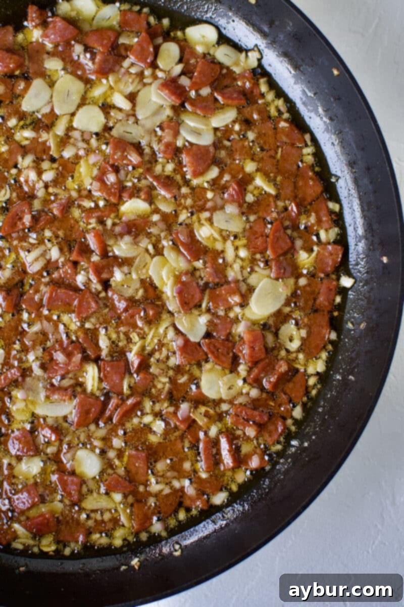 Linguine with Clams 9 Diced red onion, sliced garlic, and chunks of Spanish chorizo sizzling and caramelizing in olive oil in a skillet, creating a fragrant and savory base for the clam sauce.