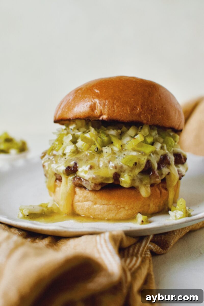 Finished Green Chili Cheeseburger, on a brioche bun, topped with hatch salsa, and cheese melting down the side, served on a rustic board.