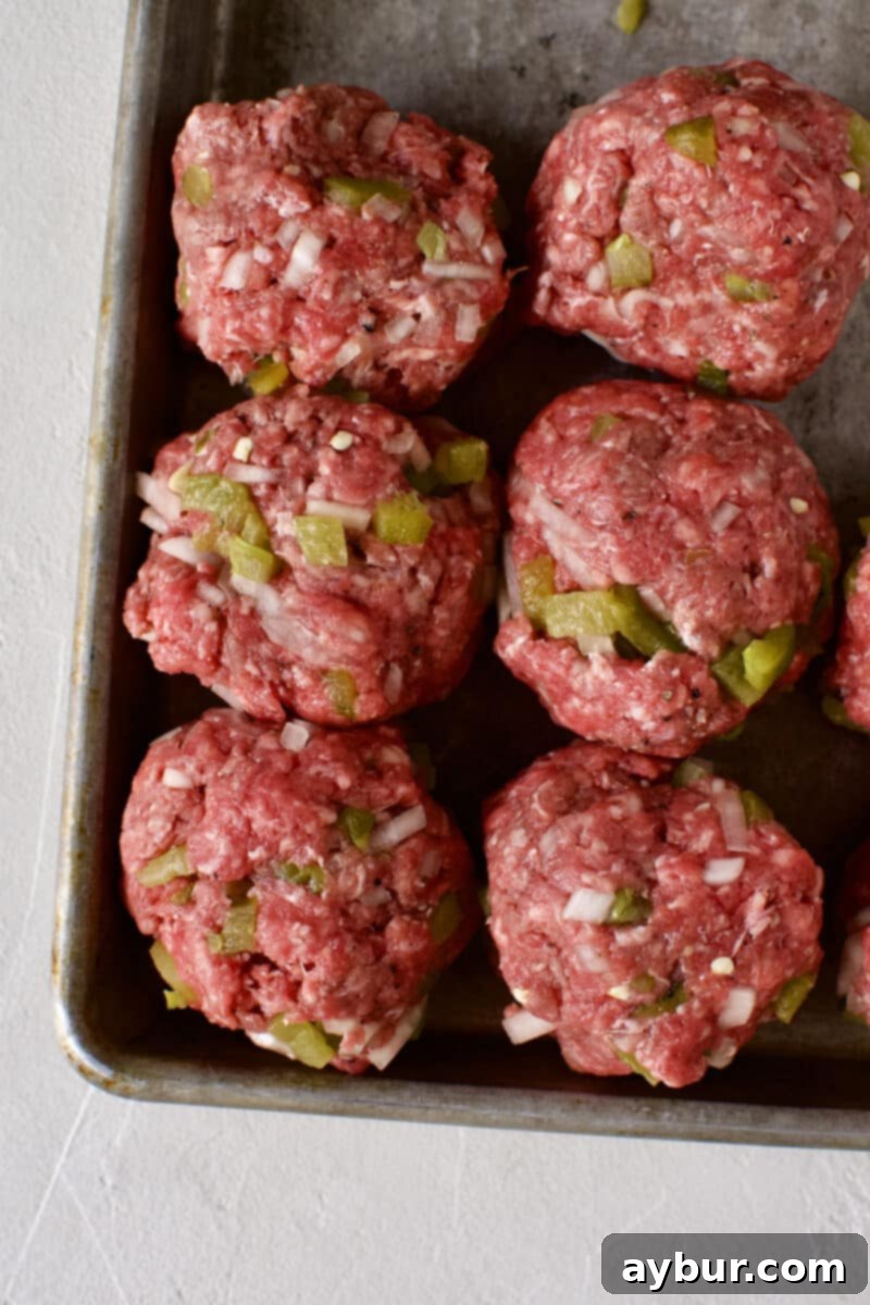 Burgers being portioned into 4 ounce balls on a cutting board.