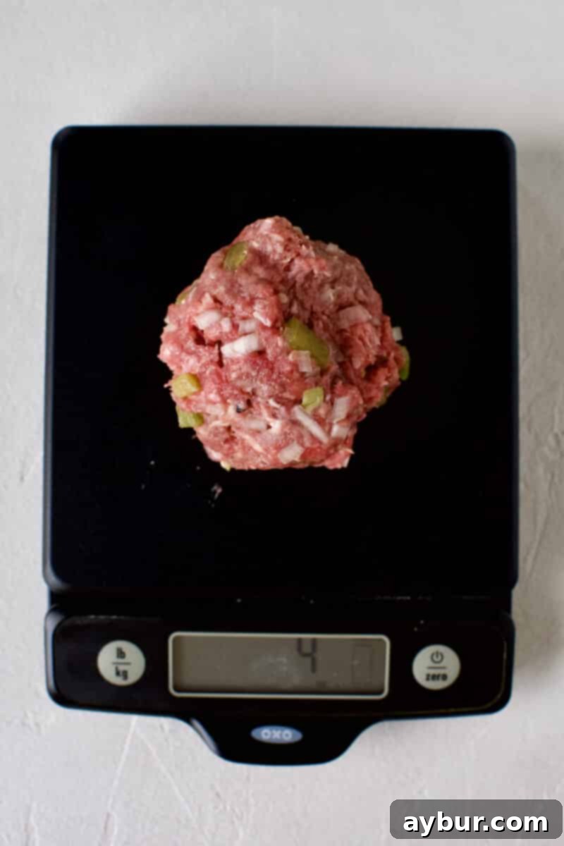Burgers being portioned into 4 ounce balls, arranged neatly.