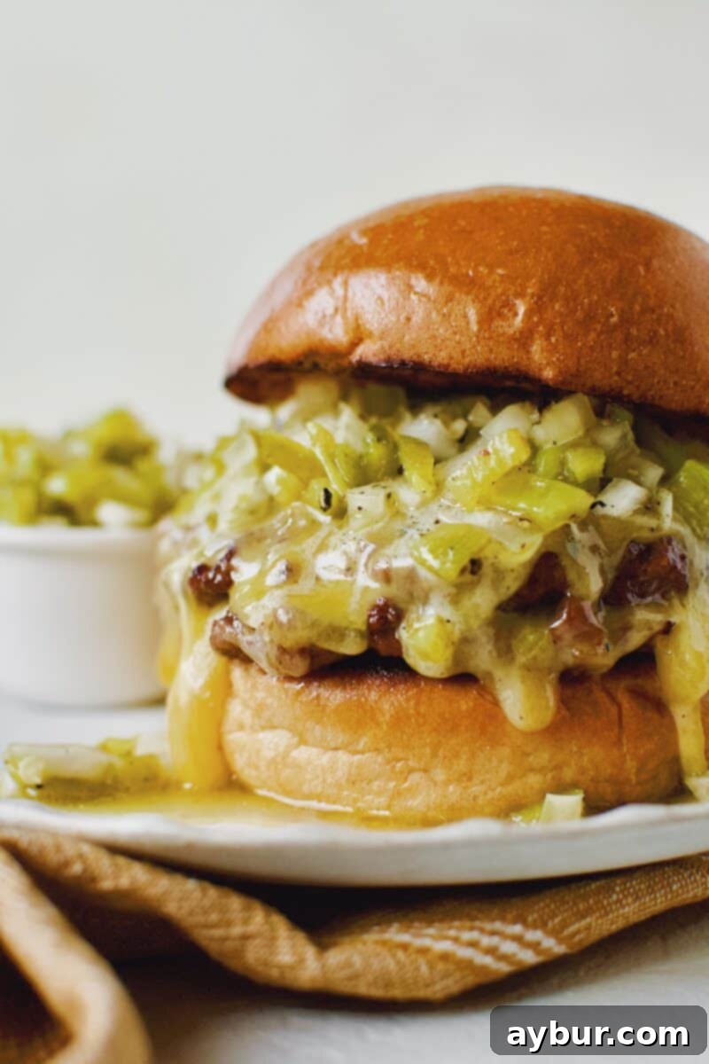 Finished Green Chili Cheeseburger, on a brioche bun, topped with hatch salsa, and cheese melting down the side, close up.