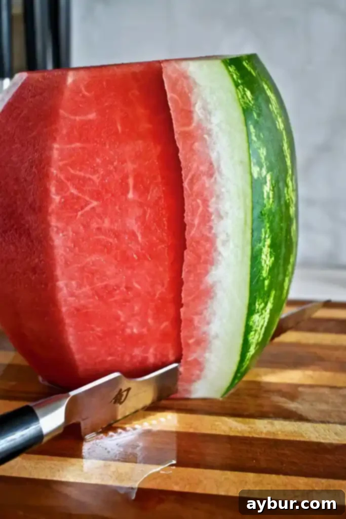 Unlock the Art of Watermelon Slicing 6 Watermelon rind being sliced off with a serrated knife.