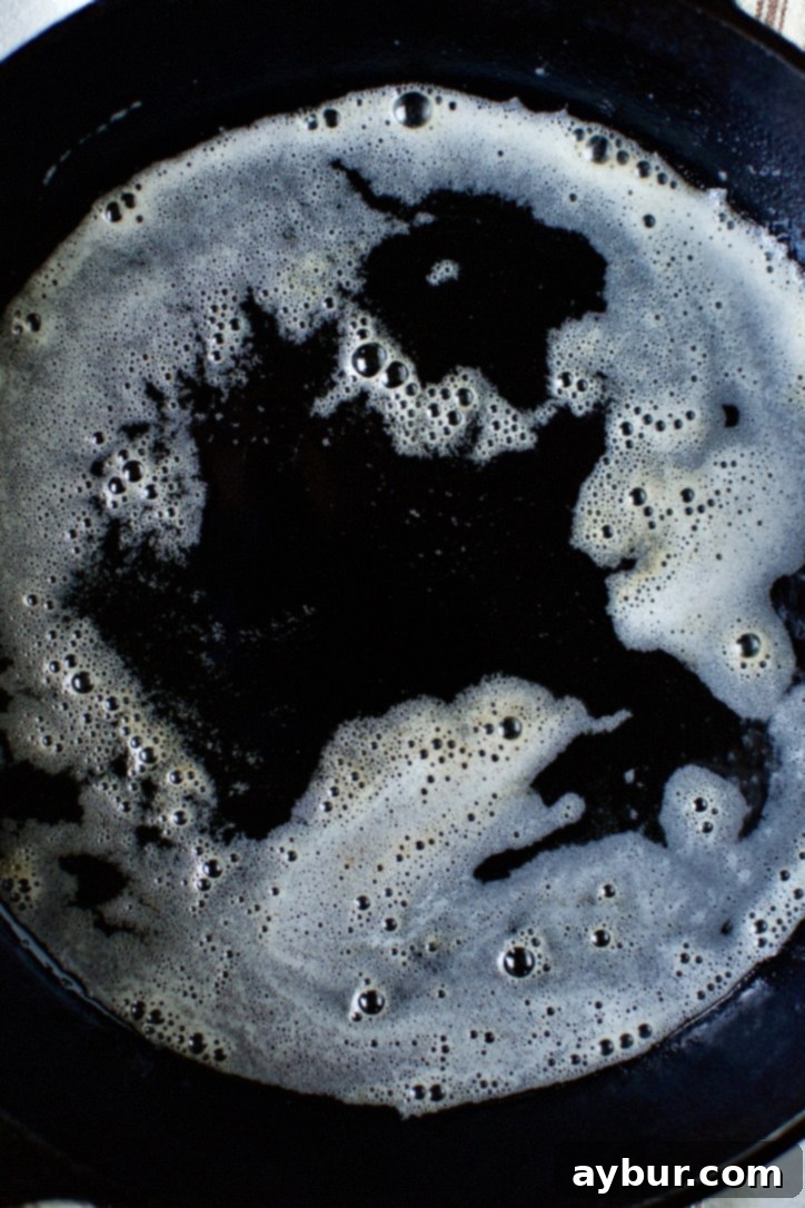 Melted butter and vegetable oil shimmering in a hot cast iron skillet, ready for French toast.