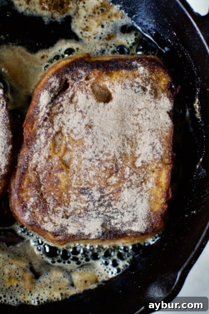 The first cooked side of the French toast, now coated with cinnamon sugar, ready for further caramelization.