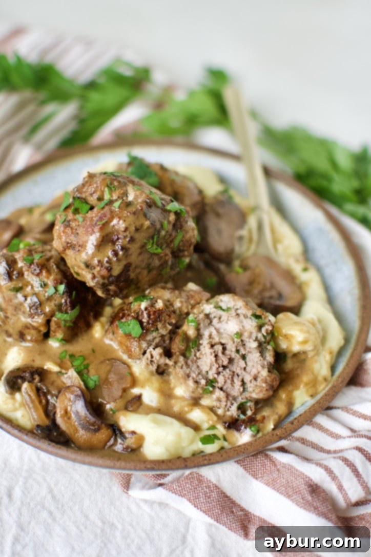 A generous serving of homemade Swedish Meatballs with creamy gravy, ready to be enjoyed over fluffy mashed potatoes.