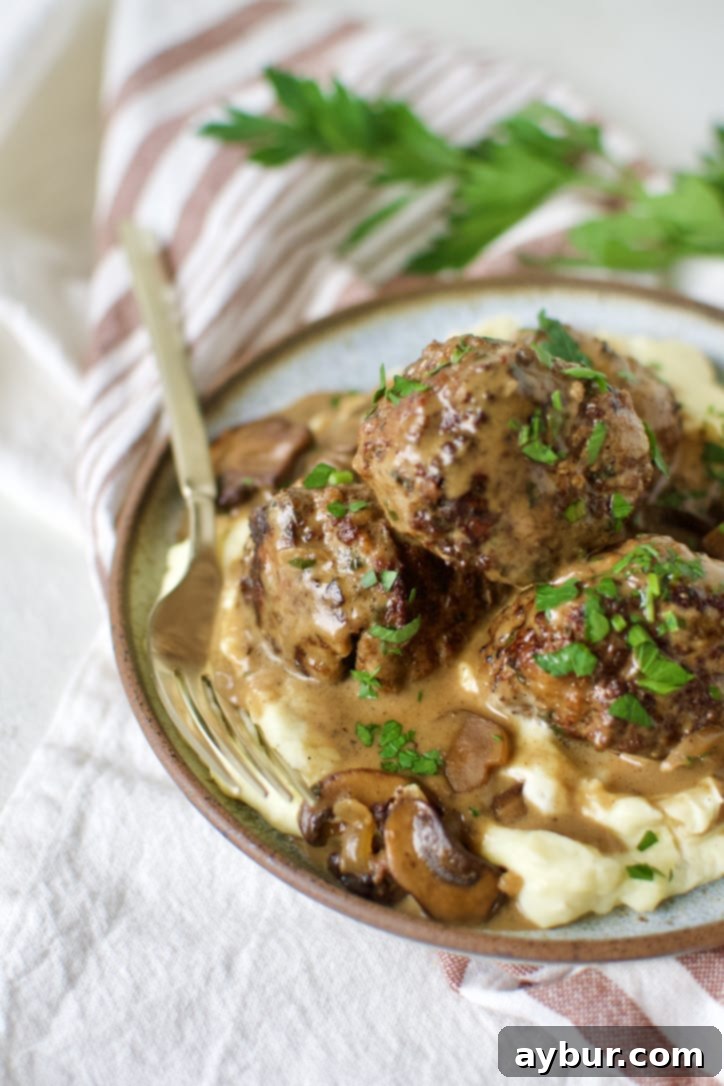 A beautifully plated dish of homemade Swedish Meatballs with mashed potatoes, garnished with fresh dill.