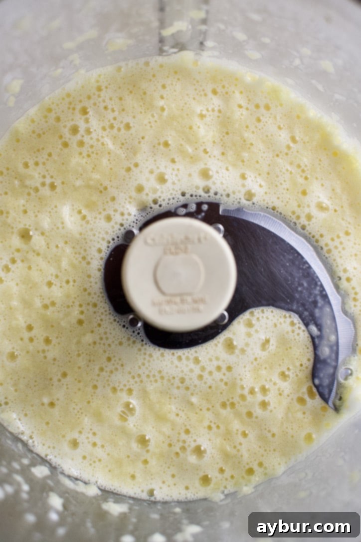 Roughly chopped onion and eggs being pureed in a food processor, creating a smooth mixture.