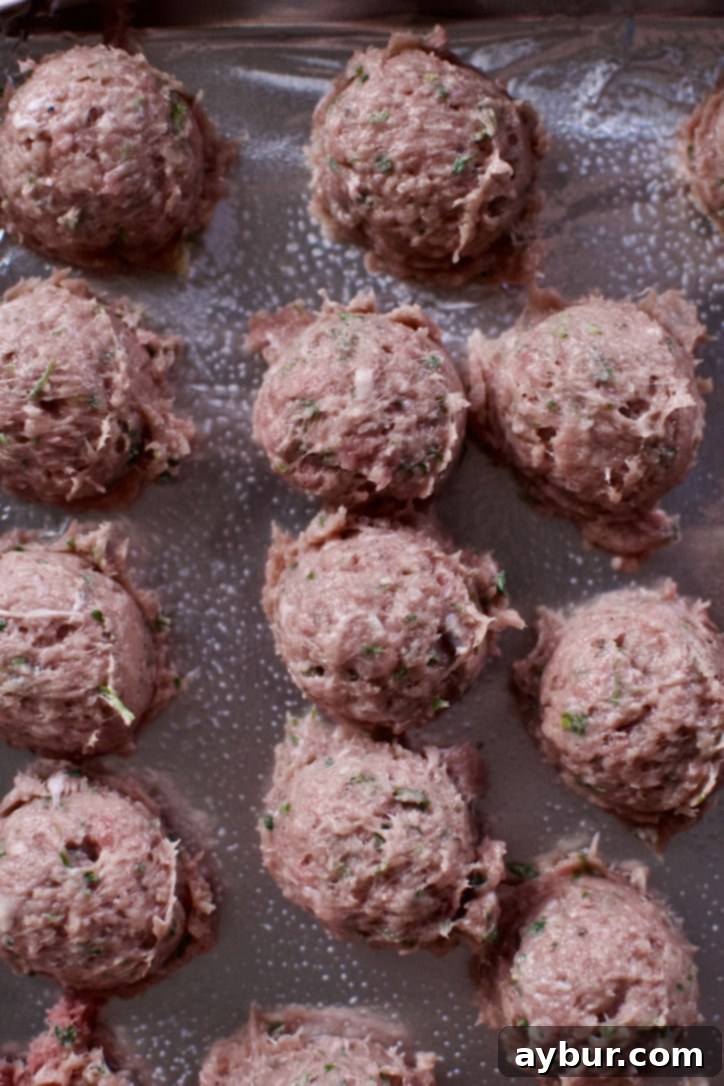 Uncooked meatball mixture scooped onto a tray, before the final rolling and shaping by hand.