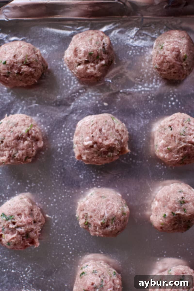 Perfectly rounded raw meatballs arranged on a baking tray, ready for cooking.