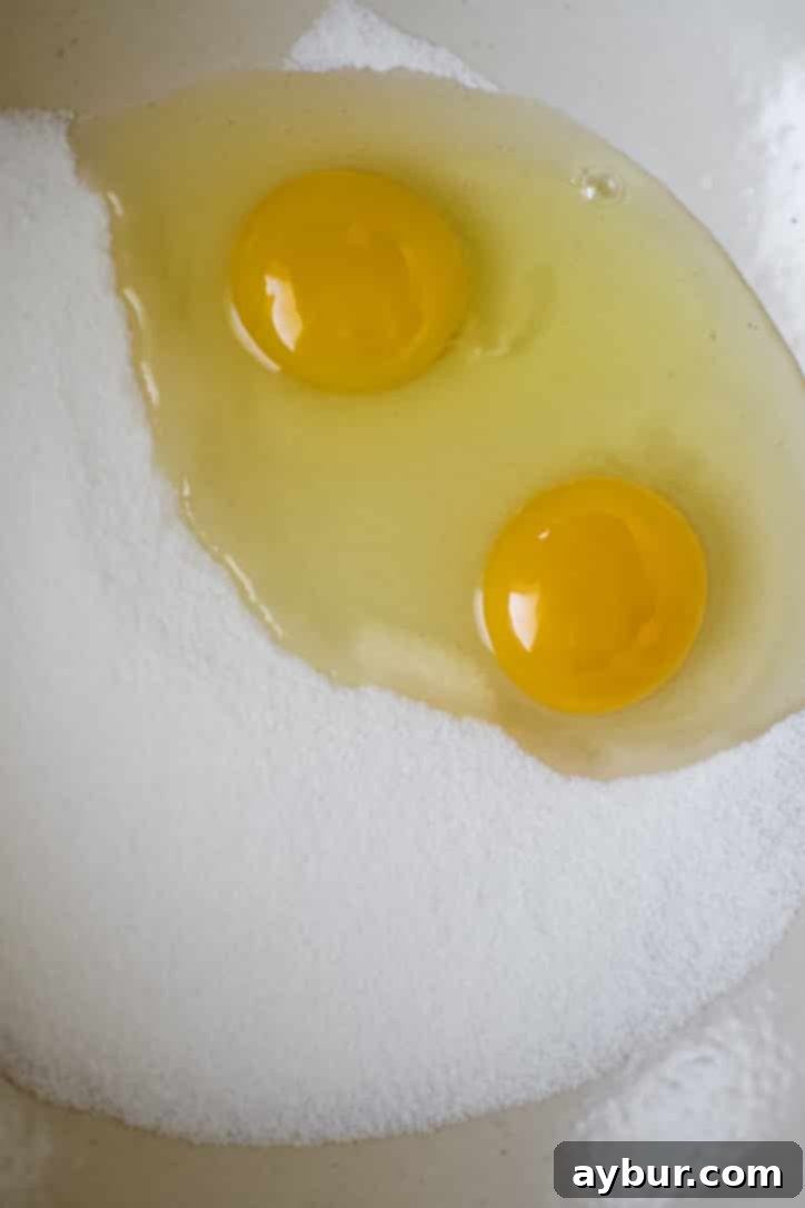 Harvest Apple Cider Donut Cake 4 Fresh eggs and granulated sugar in a mixing bowl, perfectly measured and ready to be whisked until light and foamy.