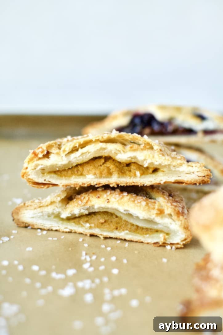 A perfectly baked Pumpkin Cheesecake Hand Pie, cut open to show the creamy, spiced filling.