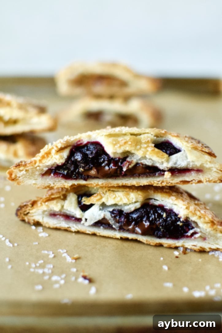 An inviting Boysenberry and Dark Chocolate Hand Pie, halved to display its luscious fruit and chocolate interior.