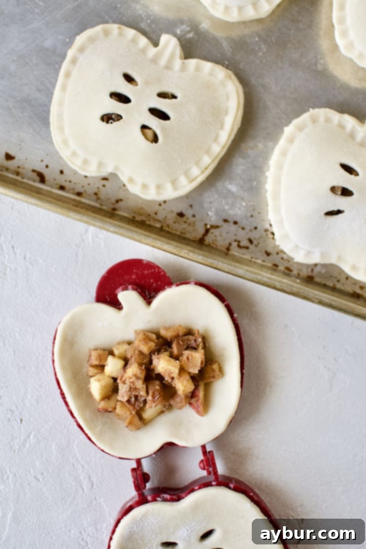 A hand pie mold being filled with the luscious apple filling, ready for sealing.