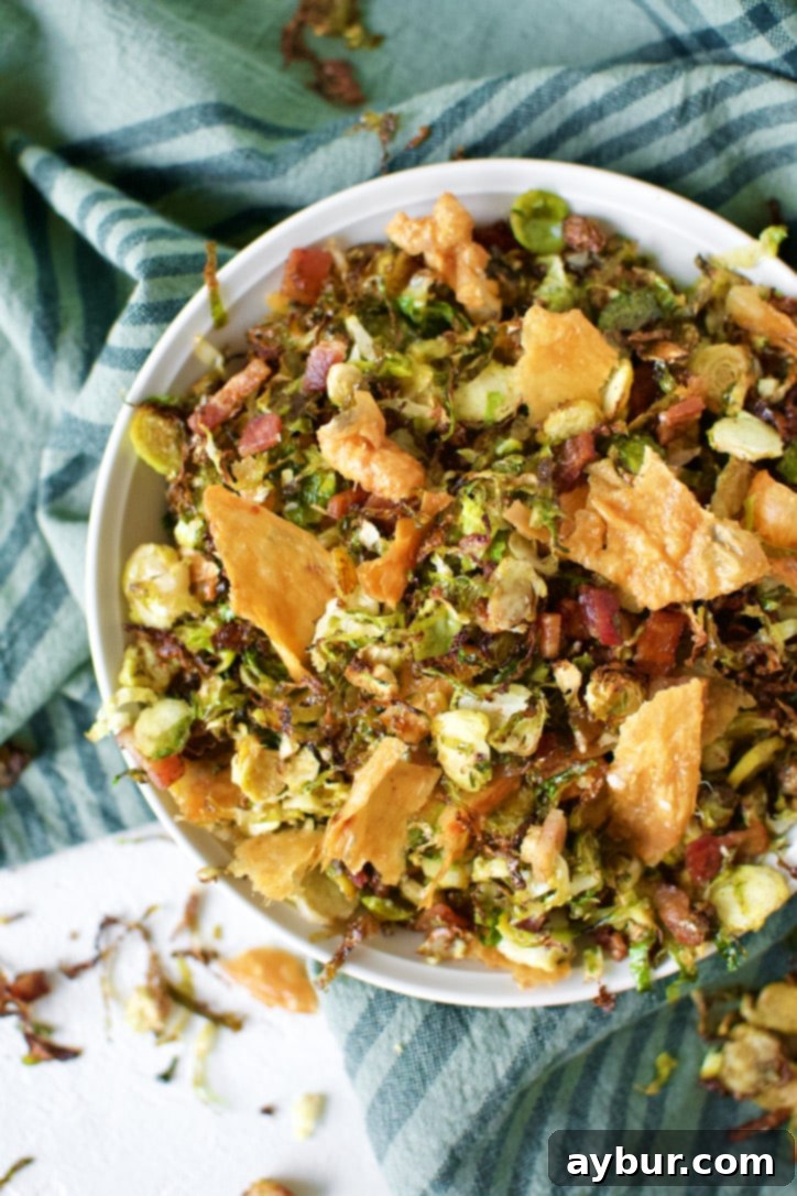 Crispy Brussels Sprouts in a bowl topped with golden brown Chicken Cracklings and bacon bits.