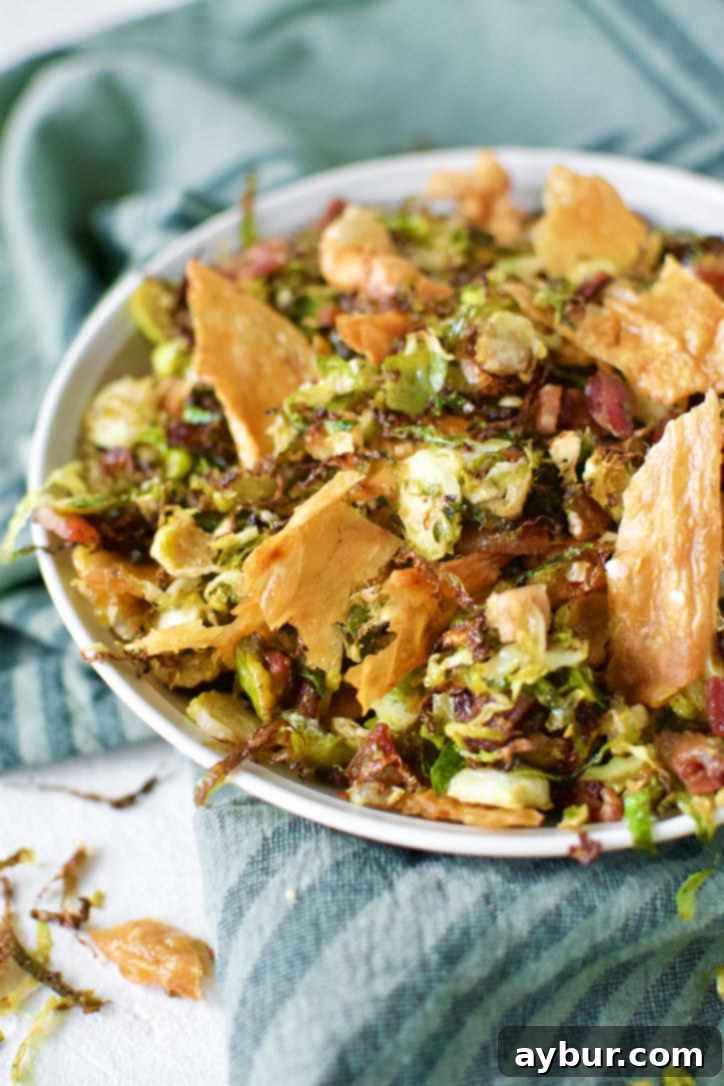 Crispy Brussels Sprouts in a bowl topped with Chicken Cracklings and bacon bits.
