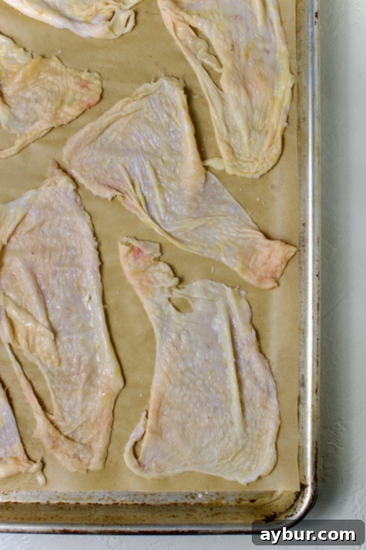 Chicken skins arranged on parchment paper for rendering.