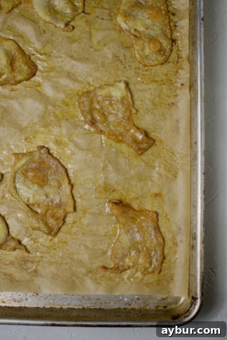 Chicken skins covered with a second sheet of parchment and a baking sheet.