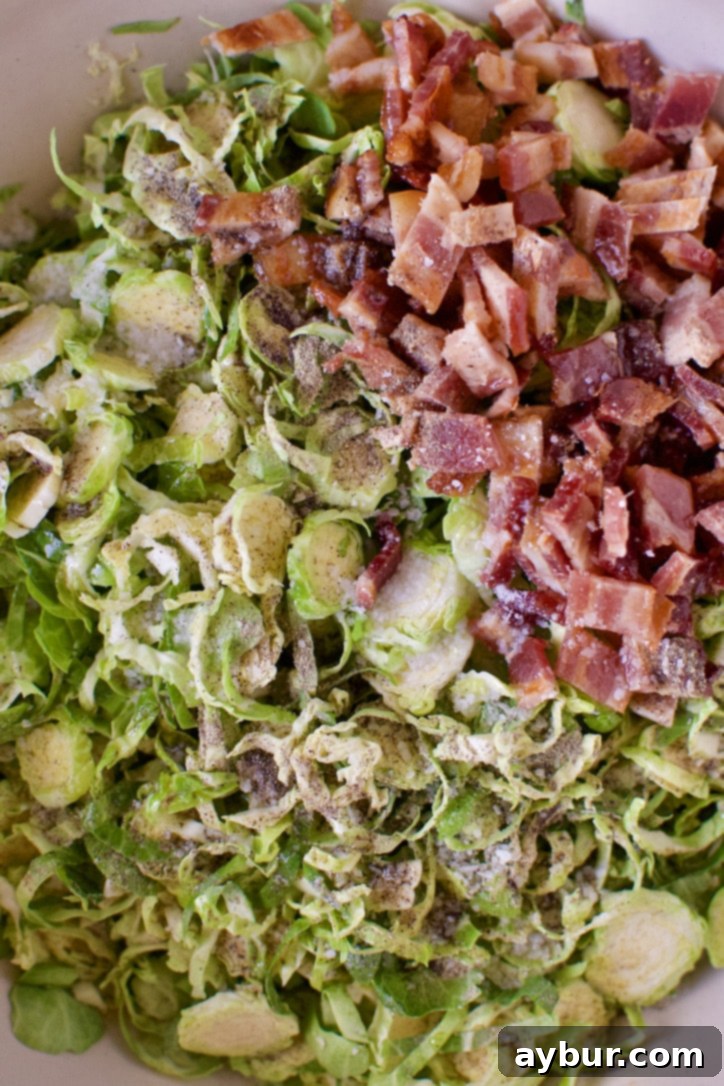 Shredded Brussels sprouts in a bowl with chicken fat and bacon.