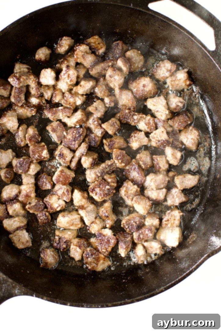 Beef Pot Pie 6 Pieces of beef stew meat sizzling and browning in a hot pan, developing rich flavor for the pot pie mixture.