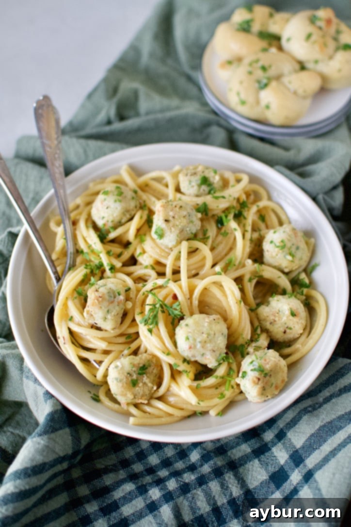 Shrimp Balls served in a white bowl over cooked bucatini pasta, garnished with fresh parsley.