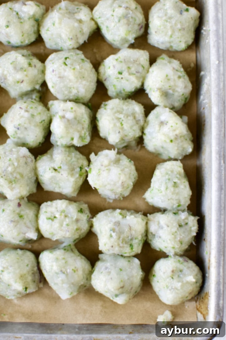 Shrimp ball mixture scooped out and portioned on a sheet pan, then smoothed into perfect spheres with wet hands.