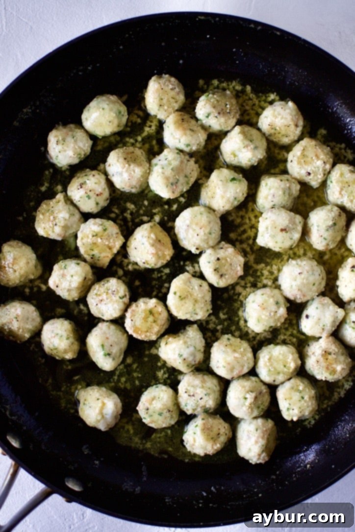 Shrimp Balls cooking in a pan with melted butter and minced garlic, turning golden brown and pink.